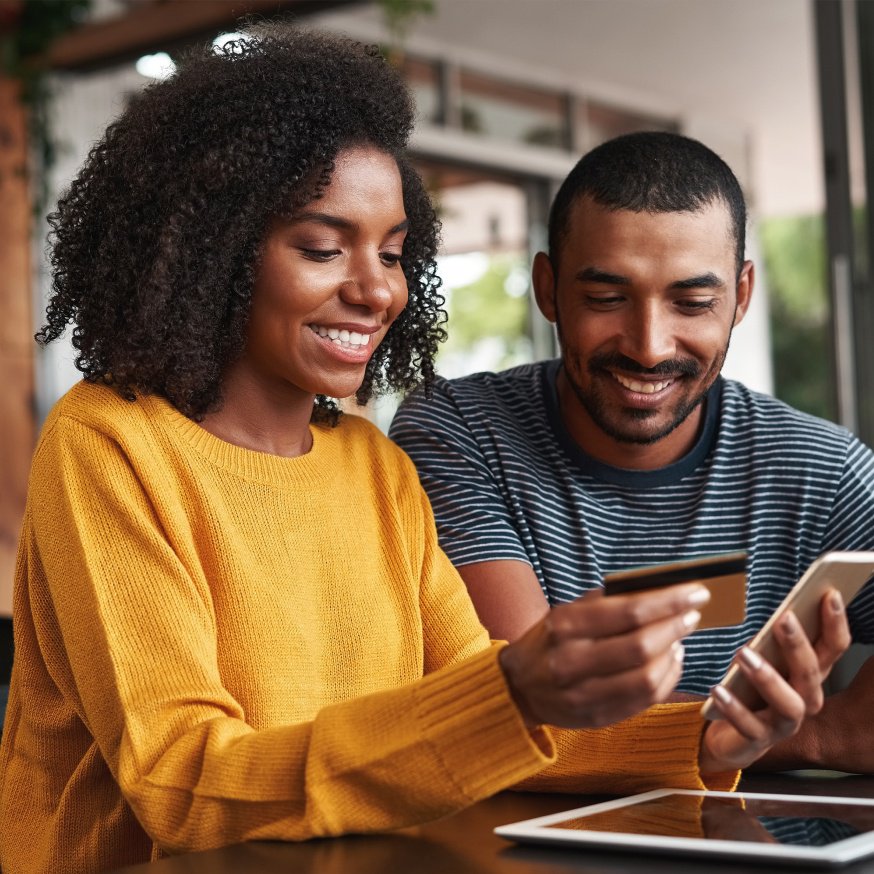 Two people looking at a credit card and phone 