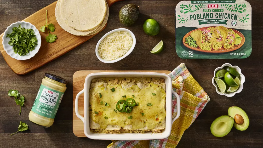 Mexican-inspired meal featuring H‑E‑B Fully Cooked Poblano Chicken, creamy poblano sauce, shredded cheese, fresh cilantro, lime wedges, avocado, and corn tortillas.