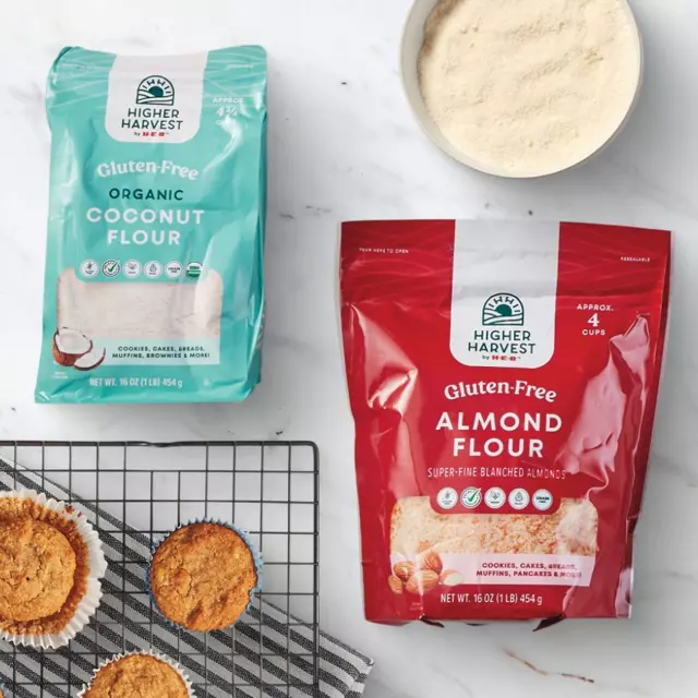 Higher Harvest by H‑E‑B Gluten-Free Organic Coconut and Almond Flour bags, a bowl of flour, and baked muffins on a cooling rack.