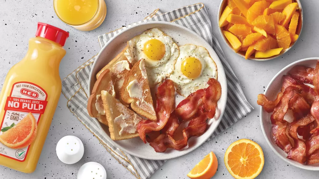 Organic orange juice, eggs, toast, bacon on a plate