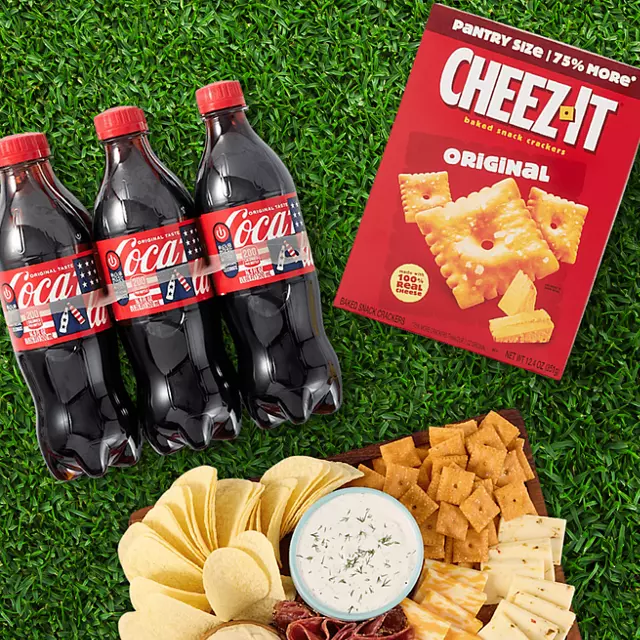 Coke bottles, CHEEZ IT box, and a spread of crackers, chips and dip