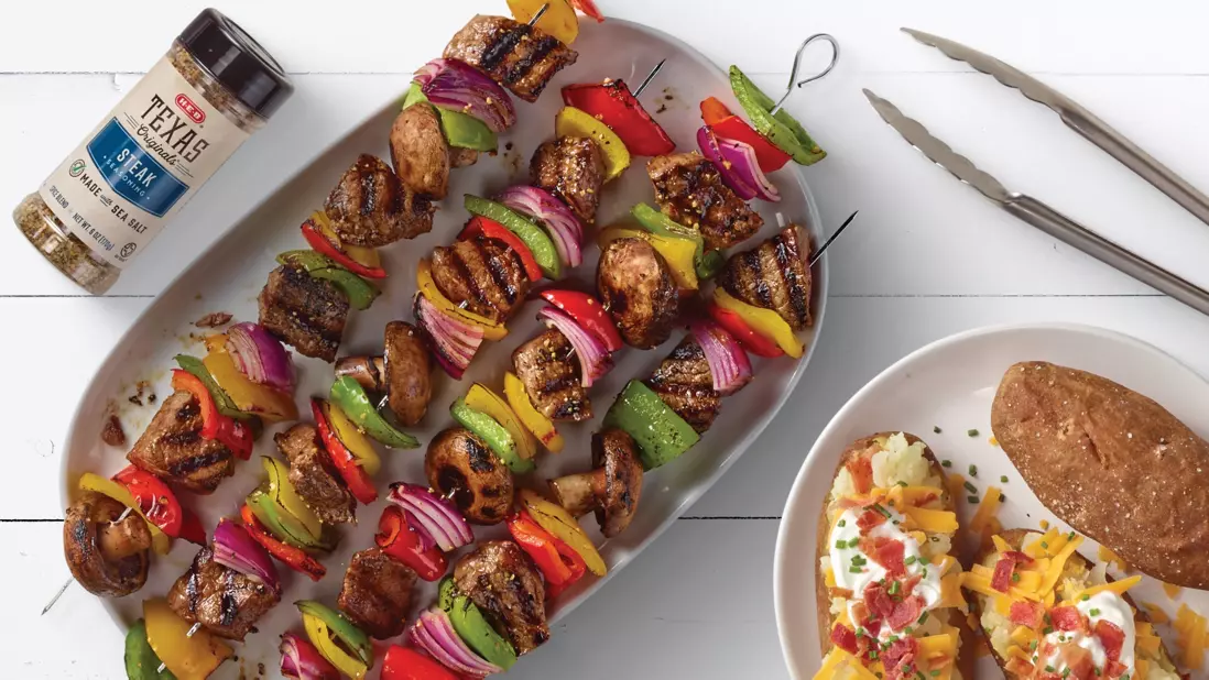 Kabobs, next to a loaded baked potato