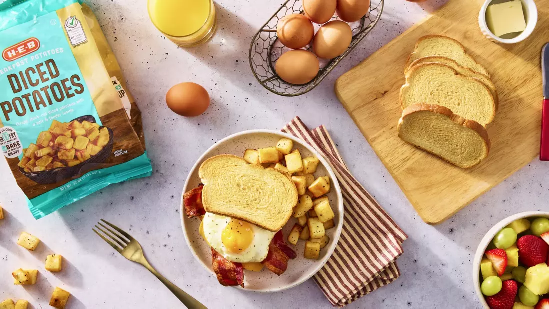 Diced potatoes, eggs, orange juice, toast, bowl of mixed fruit