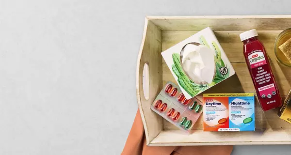 Banner promoting cold and flu season essentials featuring facial tissues, vitamin supplements, cough syrup, tea, and immunity support products on a serving tray. Text reads: “Get ready for cold season.”