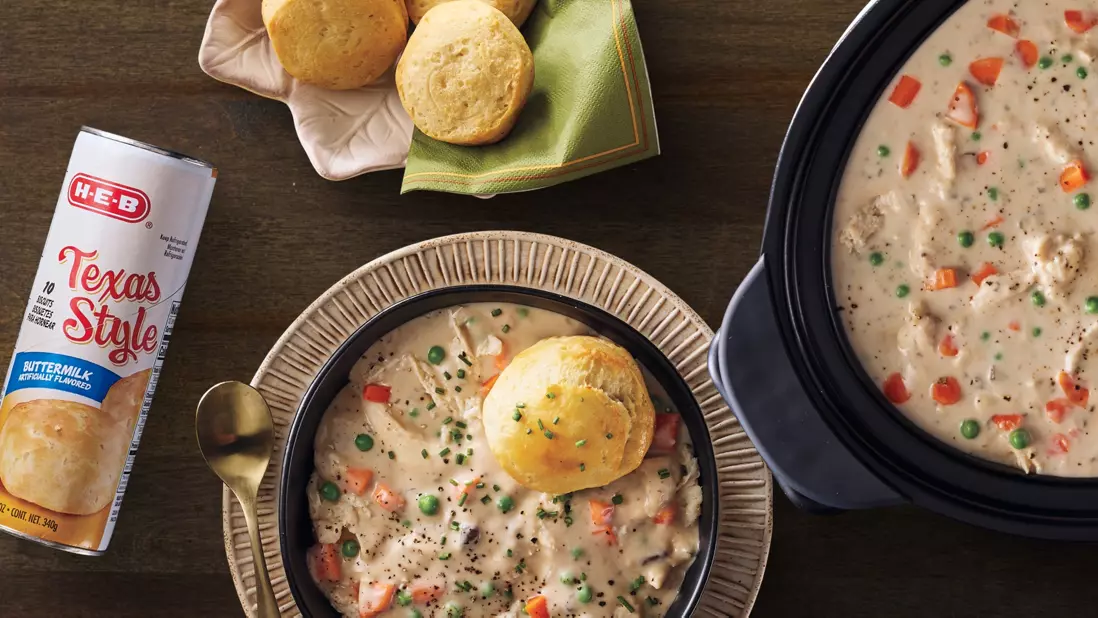 Banner featuring a bowl of creamy chicken and vegetable soup topped with a biscuit, alongside a slow cooker filled with soup, H‑E‑B Texas Style Buttermilk Biscuits, and freshly baked biscuits. The image highlights a comforting, homestyle meal.