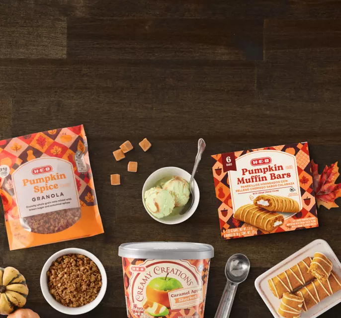 H‑E‑B pumpkin spice fall treats featuring granola, pumpkin muffin bars, caramel apple sherbet, and seasonal desserts on a wooden table.