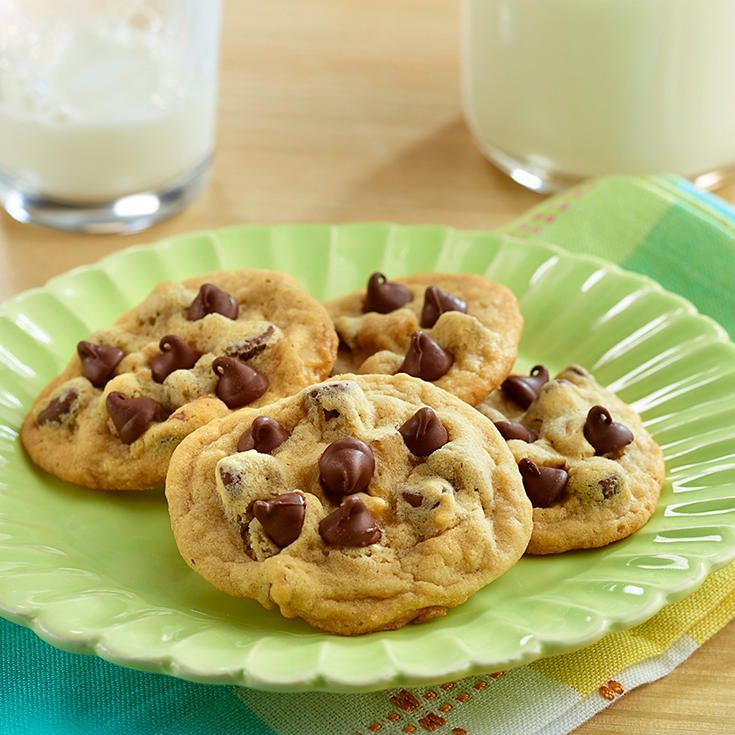 Chocolate chip cookies on a plate next to a glass of milk