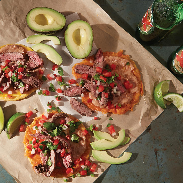 Fried cheese and beef fajita tacos topped with pico de gallo and sliced avocado on the side