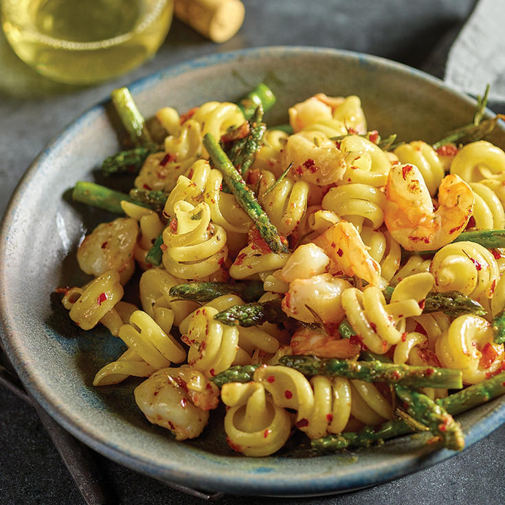 Large, spiral noodles in a bowl with shrimp and asparagus 