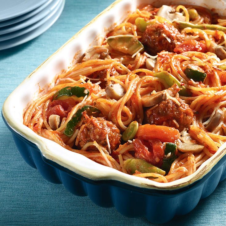 Casserole dish with spaghetti noodles, meatballs, vegetables and red sauce