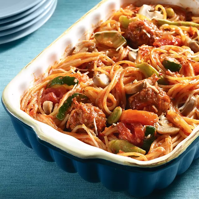 Casserole dish with spaghetti noodles, meatballs, vegetables and red sauce